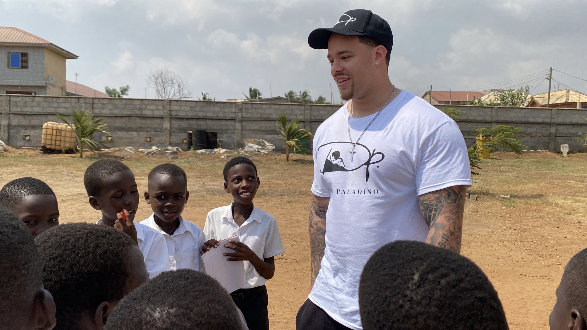 Devin Paladino outdoors in Tema, Ghana, talking with a group of schoolchildren
