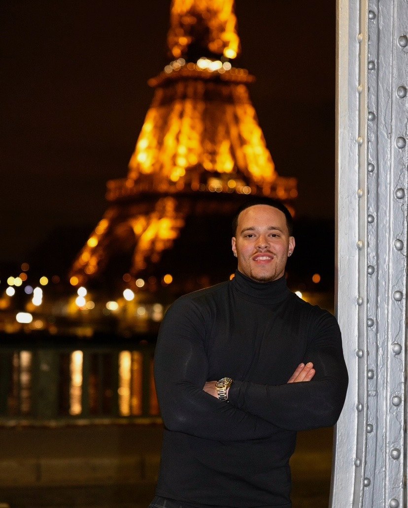 Devin Paladino in front of the Eiffel Tower at night